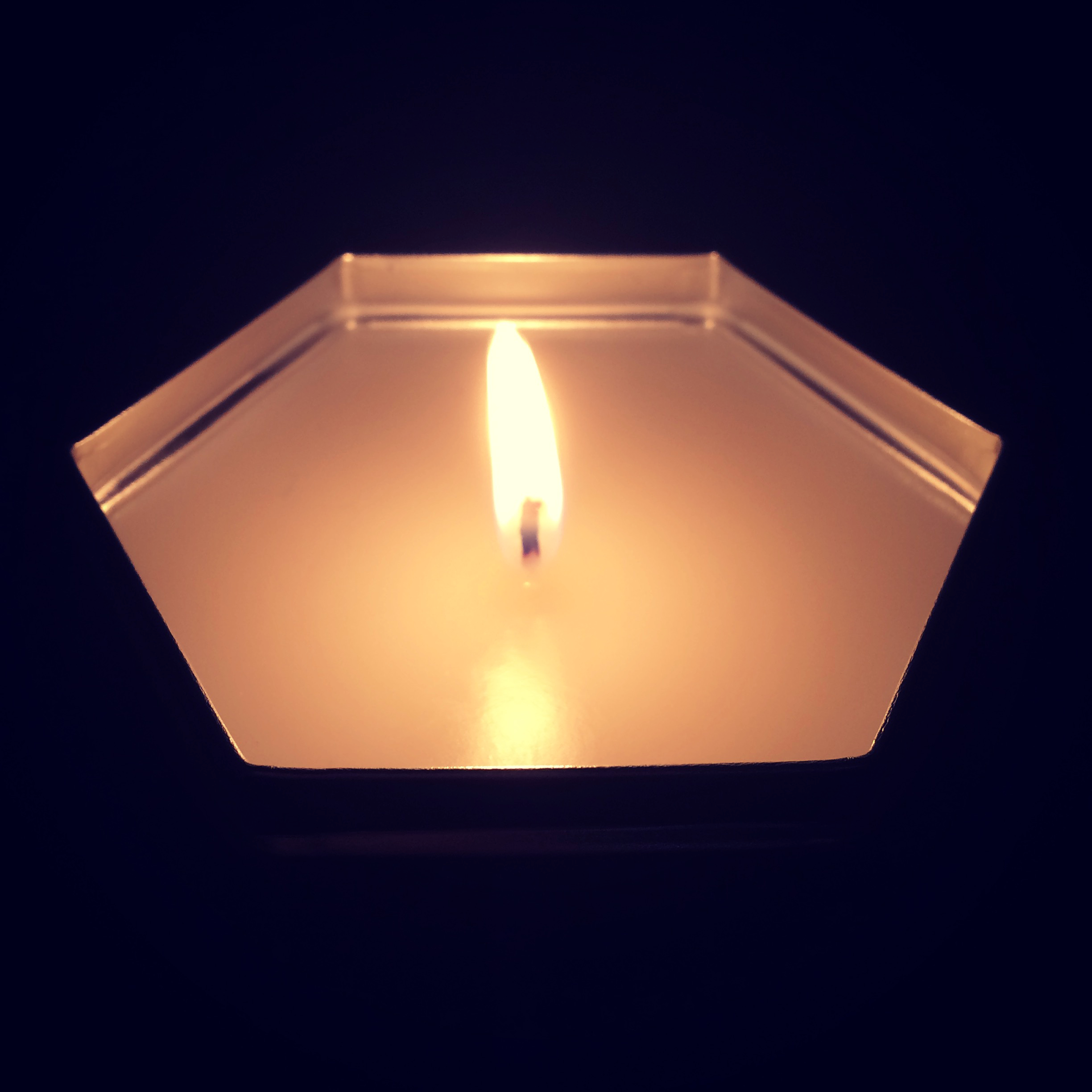 A candle in a hexagonal metal tin