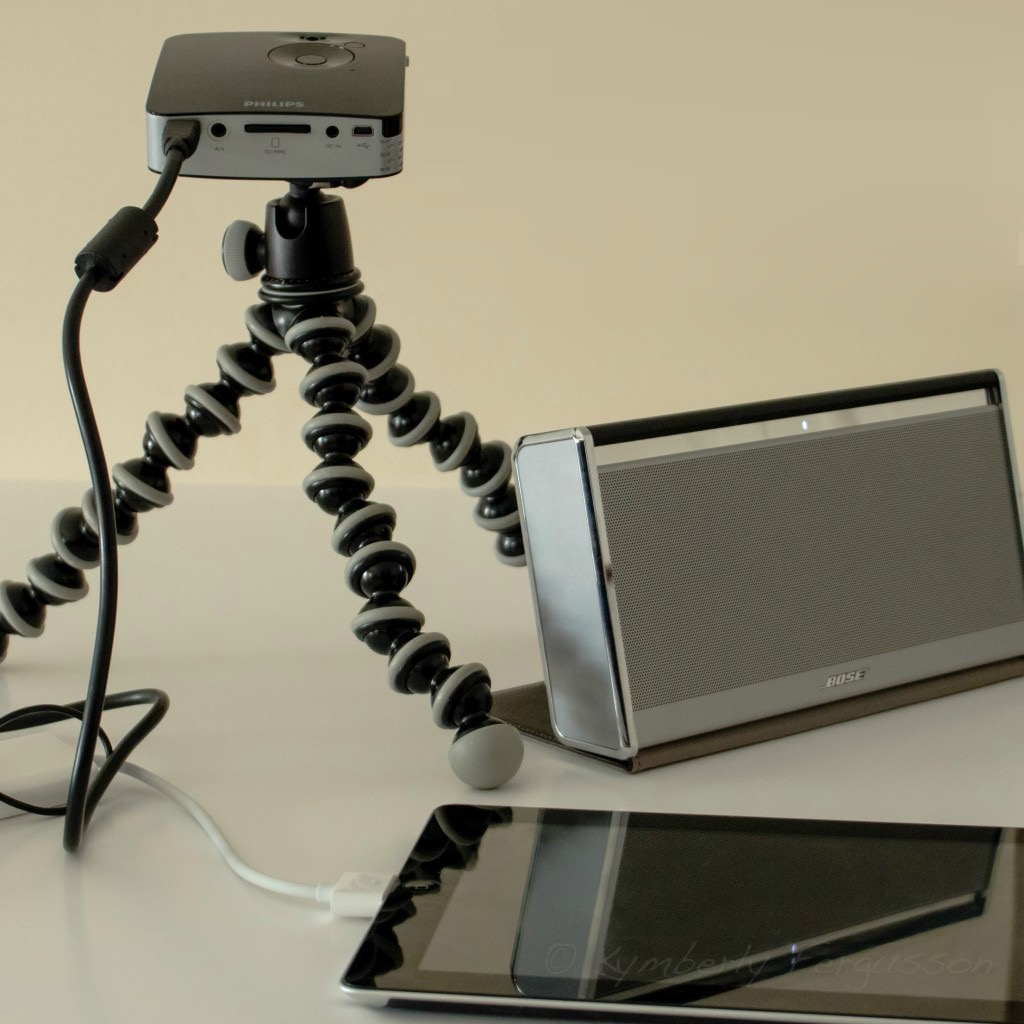 A small portable projector on a flexible tripod, a powerful Bluetooth speaker, and a tablet - the tools I use to travel to workplaces to teach conversation and textbook classes